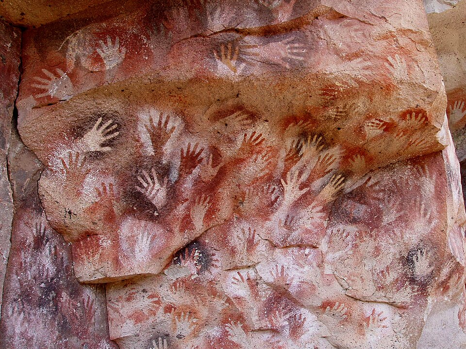 Mãos humanas em negativo pintadas numa parede rochosa